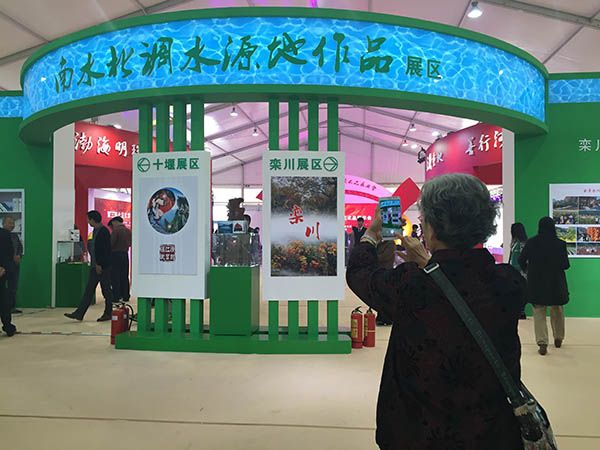 一位市民拿起手机拍摄南水北调展区