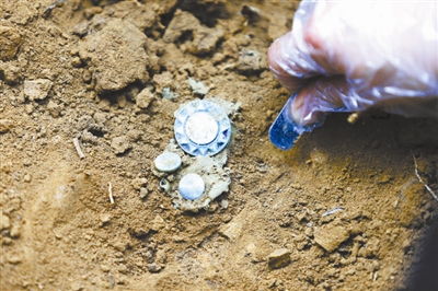 现场发掘出的帽徽 供图/龙越慈善基金会