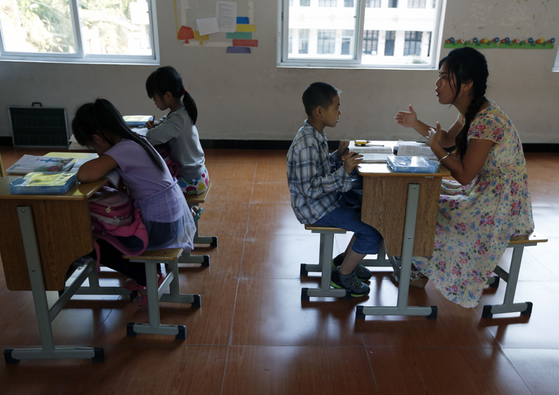 邵双双老师前半节课向郑棋颖、郑嘉丽两名3年级的女生讲解生字。教好三年的课程后，她向同一教室里的五年级男生陈凯上起了语文课。图片由cfp授权使用，严禁转载