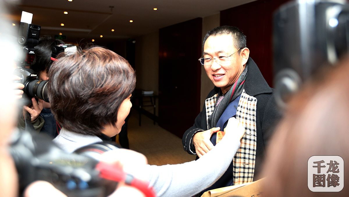 北京市十四届人大四次会议将于1月22日开幕。1月21日上午9时许，人大代表们陆续抵达驻地。工作人员为石景山代表团代表田汉佩戴出席证件。千龙网记者 王悦摄