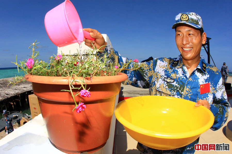 南沙东门礁的一名战士在为“太阳花”浇水，“太阳花”被誉为“礁花”，深受守礁官兵喜爱。