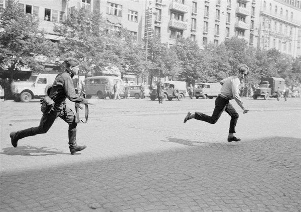 18. 在1968年的政治运动布拉格之春中，一名苏联士兵追着一个捷克人，因为他朝坦克丢石头。
