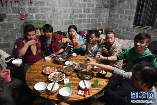 2015年2月18日，在弄勇村弄顶屯，年轻人聚在一起吃年夜饭。图片来源：新华网