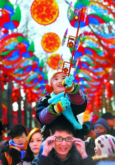 地坛庙会上，一位手持风车的小朋友骑在家长的脖子上，边走边看其乐融融。 摄影 王希宝