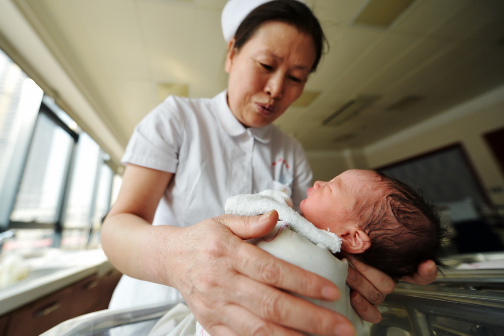 2月17日，甘肃省妇幼保健院产科护士长郭宇在新生儿护理区照顾刚出生的宝宝。