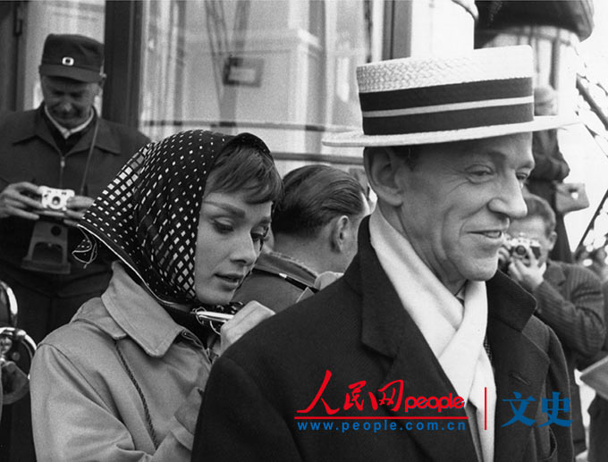 1956年7月，奥黛丽·赫本和弗雷德·阿斯泰尔在巴黎。他们正在格什温的音乐剧《甜姐儿》的拍摄现场，制片组无法应付大批法国围观者，因此他们将一些临时演员化装成警察。