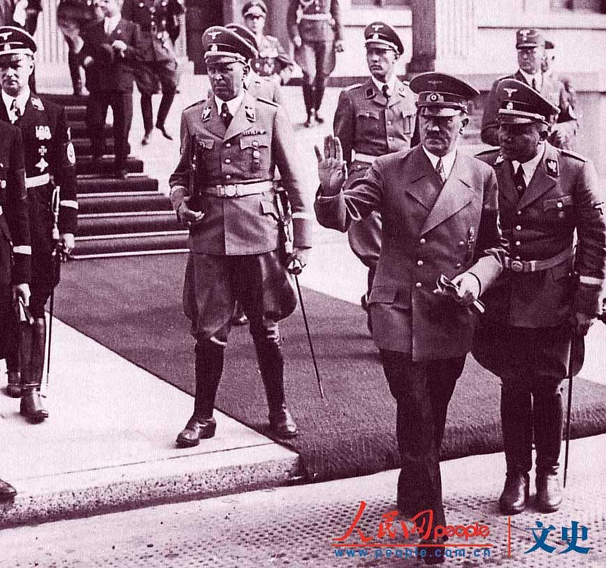 1938年，当德国代表团来参加慕尼黑会议时，马丁·鲍曼（右）设法向元首进言。鲍曼在政治上的精明和他所穿制服的颜色使他得了个“褐衫显贵”的绰号，他极度看重自己与元首的亲近，连度假也必须与元首在一起。（供图：海南出版社《第三帝国》）
