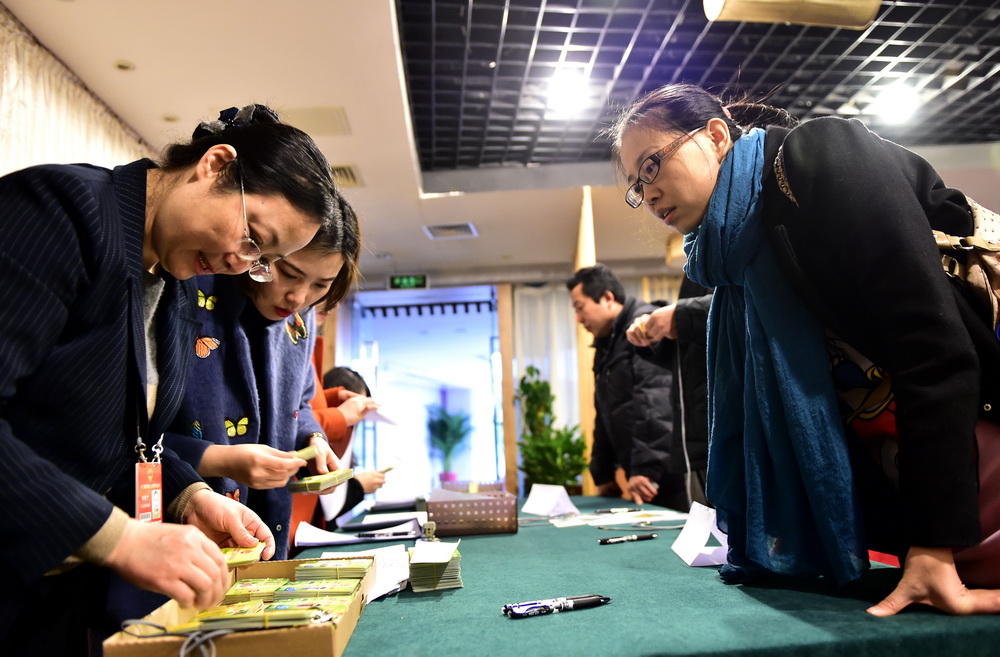 3月1日，两会新闻中心外国记者组的工作人员（左）在发放记者证。