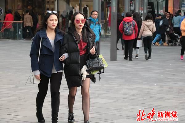 三里屯街边，姑娘上身羽绒服，下身短裙