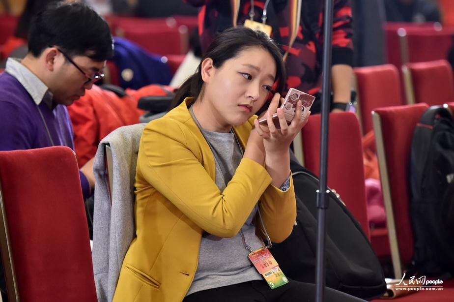 3月2日，在全国政协十二届四次会议新闻发布会现场，女记者正对着镜子化妆。（人民网记者 翁奇羽 摄）