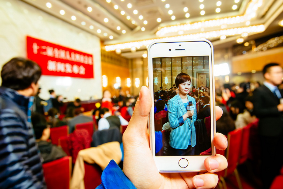 3月4日，一名记者在十二届全国人大四次会议新闻发布会开始前做出镜报道。  新华社记者张铖摄