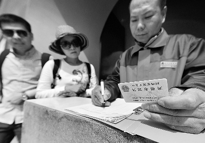 工作人员正在登记朱姓游客的身份证摄/记者 郭谦