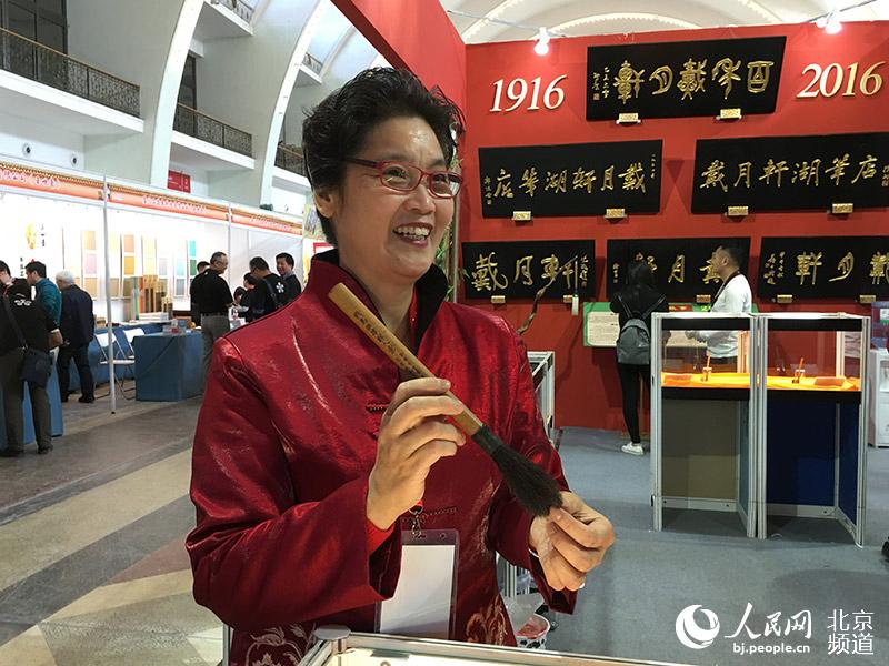 北京戴月轩湖笔店董事长于天莺在向观众介绍毛笔文化。人民网 鲍聪颖摄