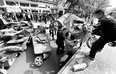 工作人员把销毁后的黑摩的清理运走 摄/黑克