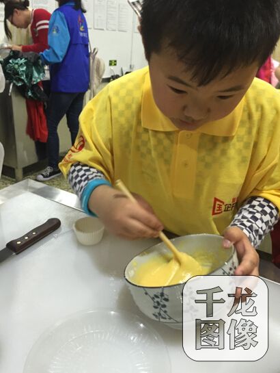 在工作人员指导下，参加活动的市民小朋友将蛋液和制作蛋糕的小麦粉打均匀。千龙网记者朱萌摄