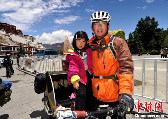 5月14日，齐海亮与女儿齐六一在出发前拍照留念。34岁的齐海亮是一位古典音乐老师，2015年9月，他带着女儿从家乡河北省唐山市出发，骑着经他改装过的自行车＋拖车的组合，开始了他们环游中国的旅行。旅行的8个多月里，他们途经天津、山东、安徽、江苏等10个省市区，骑行了1.3万多公里。“下一站是新疆。”齐海亮说，他还要用一年的时间载着女儿完成环游中国的计划，“我想带她看看我们的祖国有多大，让她近距离地感受大自然，用我自己的方式陪着她长大。中新社记者 李林 摄