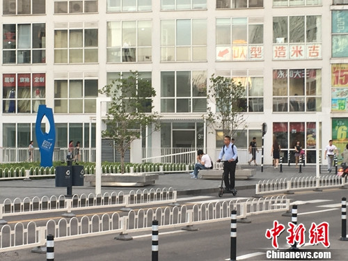 禁令出台后，北京建外SOHO附近仍有人骑电动滑板车出行。汤琪 摄