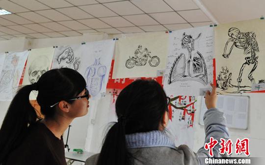 图为学生们欣赏展出的手绘解剖图