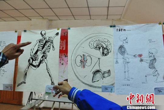 图为学生们欣赏展出的手绘解剖图