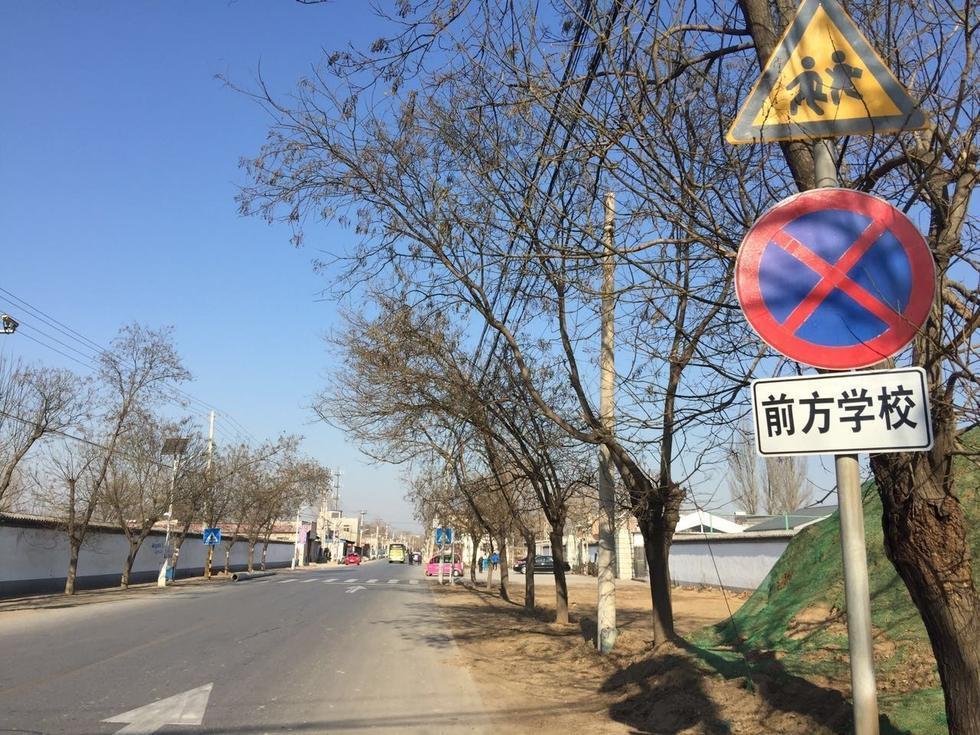 琉璃河镇务滋村南共有两所学校：务滋完全小学及南召幼儿园务滋分园，但学校前方的道路上却仅有两处提醒“前方学校”的标识，并未设有减速带。多名家长及学生向记者反映称，通行此处时总感觉十分危险。“穿村的一条路，车很多，而且司机基本都不减速，上学、放学的时候还算好一些，平时都是呼啸而过。”图为学校前方无减速带，仅有两处设有“前方学校“的标识。