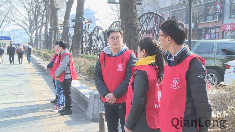 全国两会召开之际，大街上一群身穿红马甲的慈善义工在路上进行巡查工作。