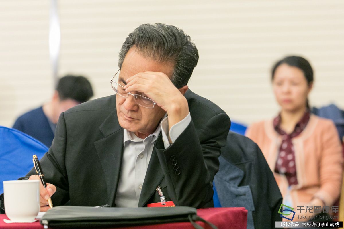 图为小组会现场委员认真听取审议报告意见，并不时记录。