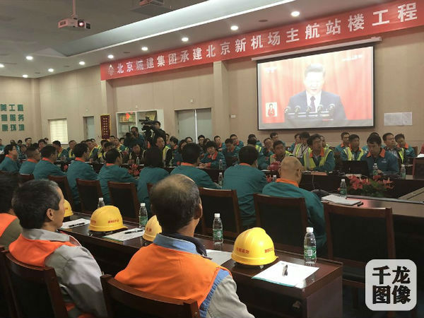 身着橘黄色反光背心的工人代表收看中国共产党第十九次全国代表大会开幕会。