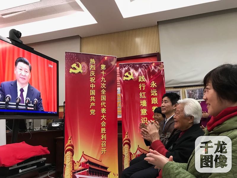 中国共产党第十九次全国代表大会10月18日在人民大会堂隆重开幕。图为在西城区西交民巷社区居委会内，22名社区党员、辖区单位党员以及社区干部群众，齐坐在电视机前，认真收看学习记录习总书记的大会报告。千龙网记者 秦胜南摄 