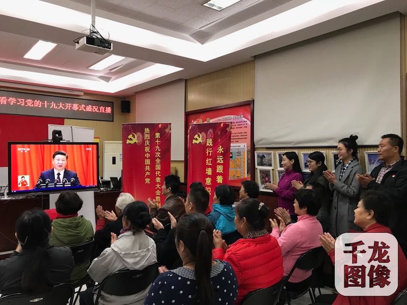 中国共产党第十九次全国代表大会10月18日在人民大会堂隆重开幕。图为在西城区西交民巷社区居委会内，22名社区党员、辖区单位党员以及社区干部群众，齐坐在电视机前，认真收看学习记录习总书记的大会报告，与现场代表一起鼓掌，对中国取得伟大成就一同欣喜，对未来的发展充满无比期待。千龙网记者 秦胜南摄