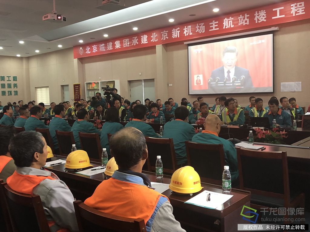 身着橘黄色反光背心的工人代表收看中国共产党第十九次全国代表大会开幕会。