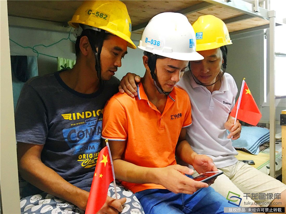 图为中建二局深圳分公司南山外国语高中项目部农民工党员唐柯正在和工友们在宿舍用手机收看十九大开幕会。