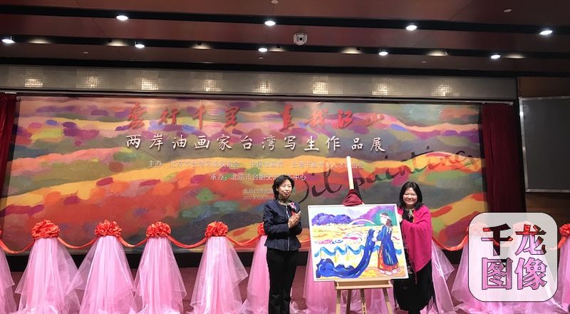 20日,“爱行千里•画我江山”两岸油画家台湾写生作品展在北京台湾会馆举行。图为台湾画家吴和珍(右一)赠送画作。市台联供图 千龙网发