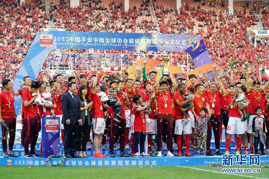 11月4日，广州恒大队球员郑智（中）在颁奖仪式上高举奖杯与队友、教练、家人共同庆祝夺冠。新华社记者刘大伟摄