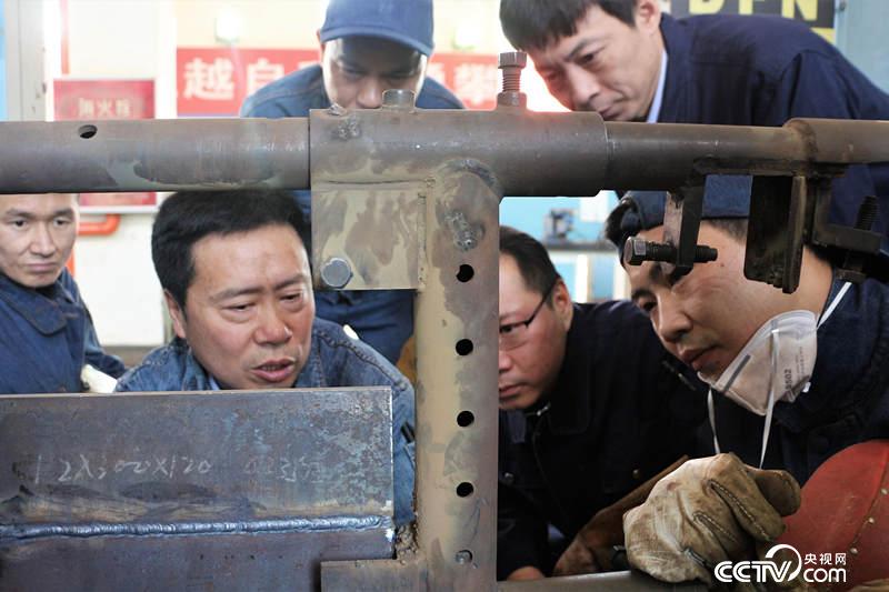 孔建伟（左二）和同事们在车间交流焊接技术。（记者何川摄）