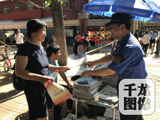 6月7日，北京市朝阳区和平街街道城管为陪考家长递去报纸，同他们热情交谈