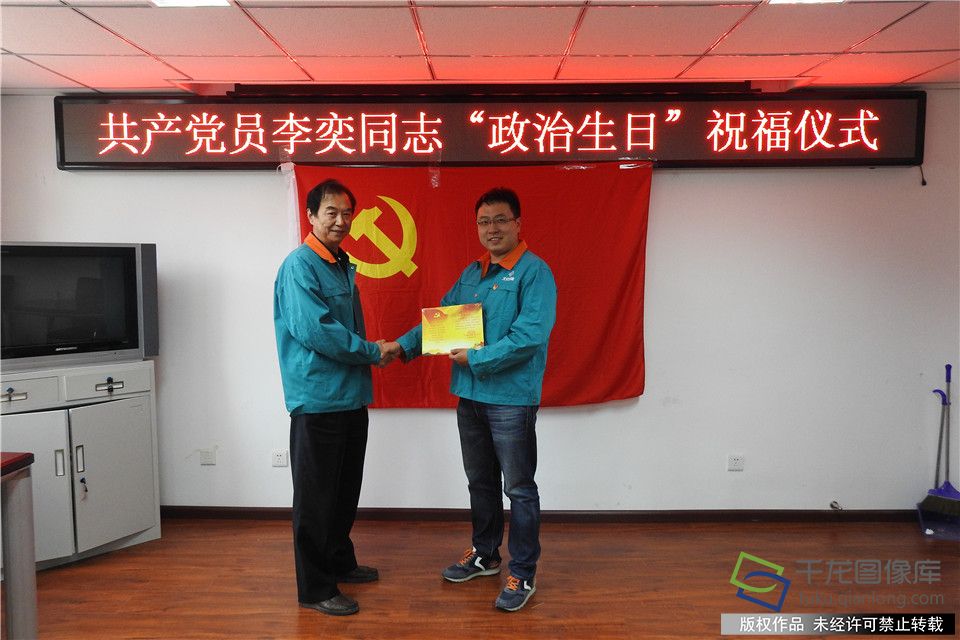 北京城建二机电公司党总支书记马振江（左）与过政治生日的党员李奕握手祝贺