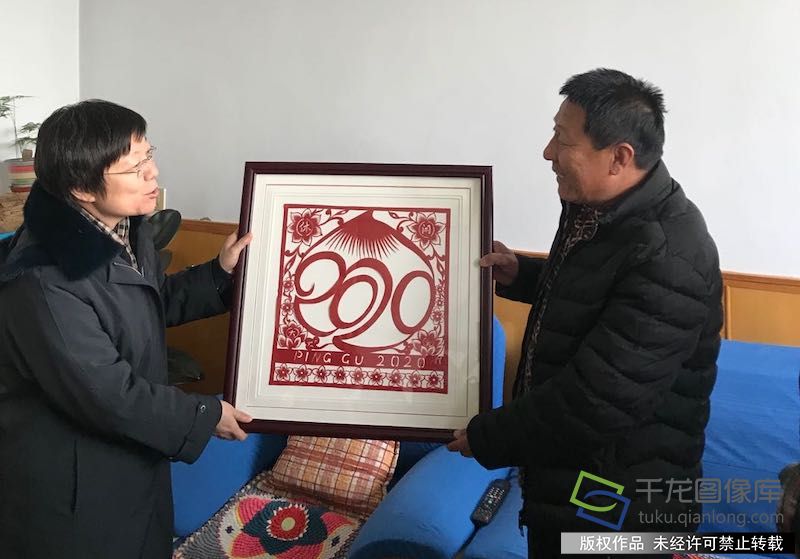 1月29日,平谷区举办“扮靓休闲平谷,美在桃乡农家” 文艺进农家活动。图为平谷区区委常委、宣传部长王红艳(图左)向村民赵胜利(图右)送上剪纸作品。秦胜南摄 千龙网发