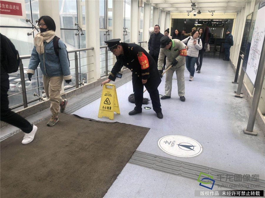 地铁工作人员在站内铺设防滑垫，立防滑牌