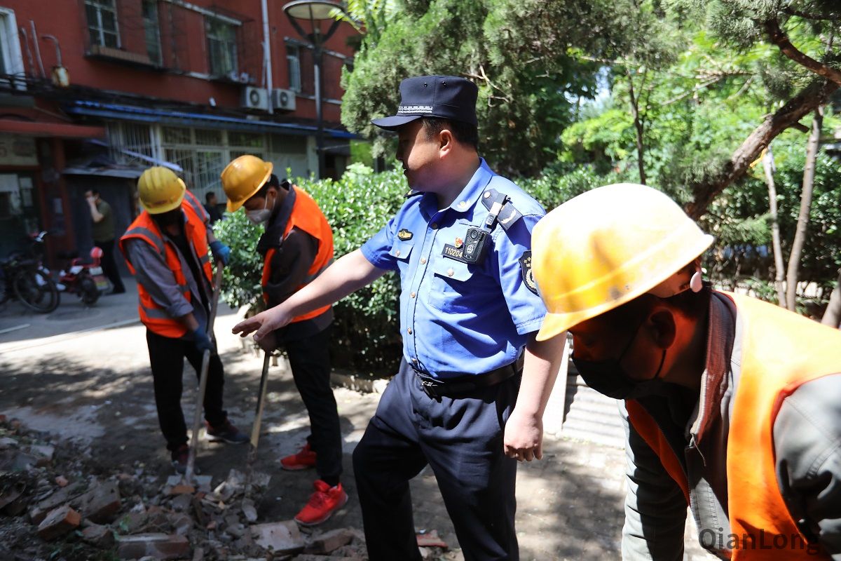 5月13日上午，展览路街道启动“街道吹哨，部门报道”工作机制，组织街道城管执法队、派出所、工商所、食药所、居委会，对月坛北街25号院55门北侧用于经营的老旧违建进行拆除，拆除面积15平方米。图为西城区展览路街道第二城管执法队队员协助施工人员清运渣土。