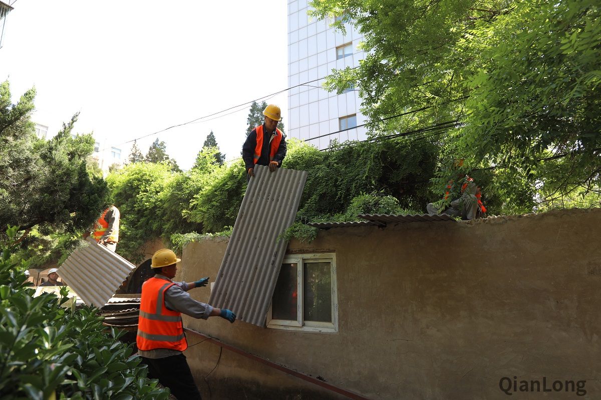 5月13日上午,展览路街道启动“街道吹哨,部门报道”工作机制,组织街道城管执法队、派出所、工商所、食药所、居委会,对月坛北街25号院55门北侧用于经营的老旧违建进行拆除,拆除面积15平方米。图为施工人员正在拆除违法建设的石棉瓦屋顶。