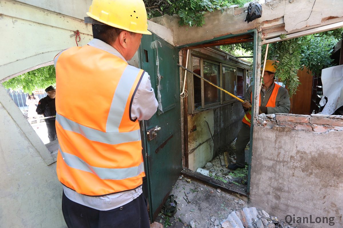 5月13日上午，展览路街道启动“街道吹哨，部门报道”工作机制，组织街道城管执法队、派出所、工商所、食药所、居委会，对月坛北街25号院55门北侧用于经营的老旧违建进行拆除，拆除面积15平方米。图为施工人员进行拆除工作。