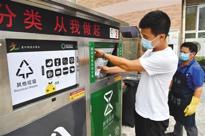 7月30日，东城区新世界家园，居民将一袋厨余垃圾投入装有破袋器的垃圾桶，破袋器会打破塑料袋，倾倒垃圾，再将塑料袋转入其他垃圾桶中。新京报记者 吴江 摄