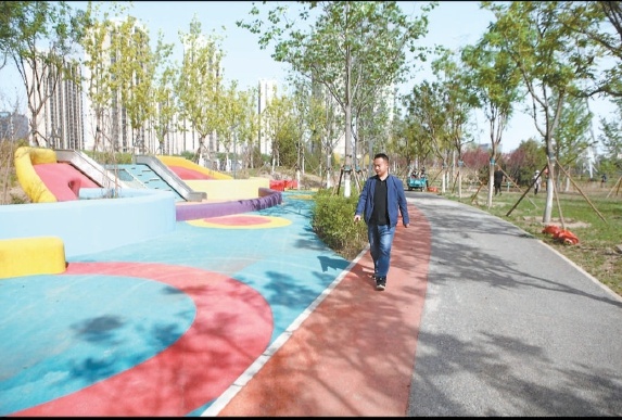 市民在西铁营公园健身步道散步。 通讯员 胡博摄