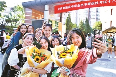 在北京十八中考点外，多名考生手捧鲜花与家长合影摄影/本报记者 郭谦