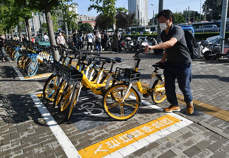 近期，为了解决共享单车无序停放、扎堆淤积、占道拥堵等乱象，东城区城管委梳理了相关“接诉即办”的高发点位和时段，与共享单车企业进行技术联调，在王府井商圈、崇文门商圈和天坛景区等周边形成“一区一策”治理模式。目前，东城区在8处地铁站推行共享单车“入栏结算”。图为：崇文门站外，地面施划了几块区域，黄底白字标注“入栏结算停放区”，一位市民正在将使用完的共享单车停车入位。