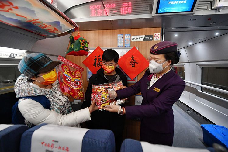 列车工作人员为旅客送上虎年福字。  