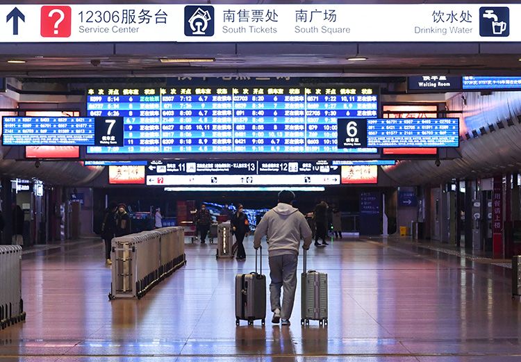 北京西站，旅客拉着行李箱走向候车室。