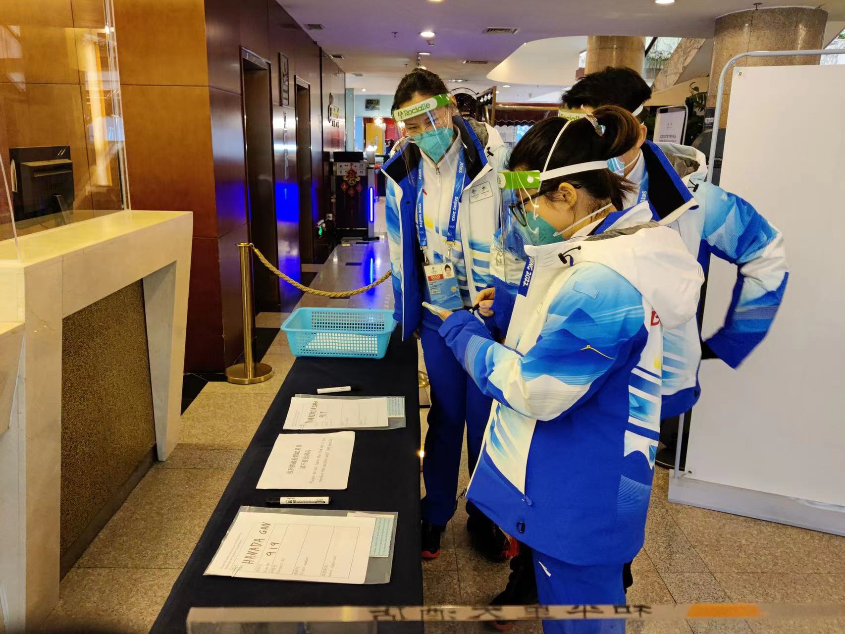 和平里大酒店三位志愿者查看外宾入住登记表,分析客人办理入住过程中可能遇到的问题,商讨解决方案及沟通用语。