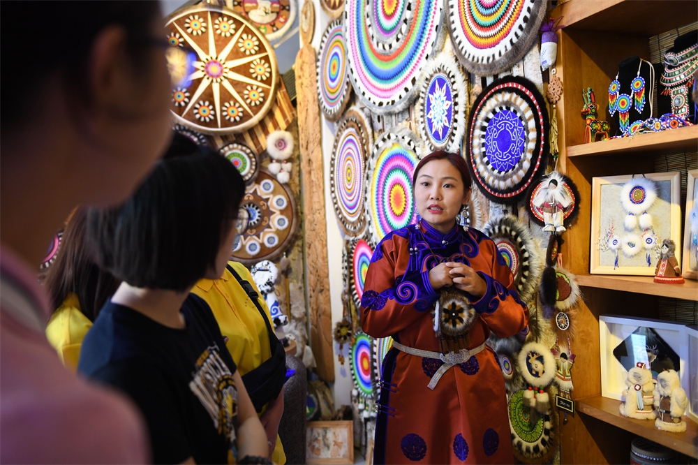 鄂温克旗非遗传承人艾吉玛（右一）为参访大学生讲解&ldquo;太阳花&rdquo;的创意来源及制作工艺。受访者供图