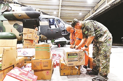 部队官兵和物美集团工作人员连夜对执行任务的直升机进行装载作业